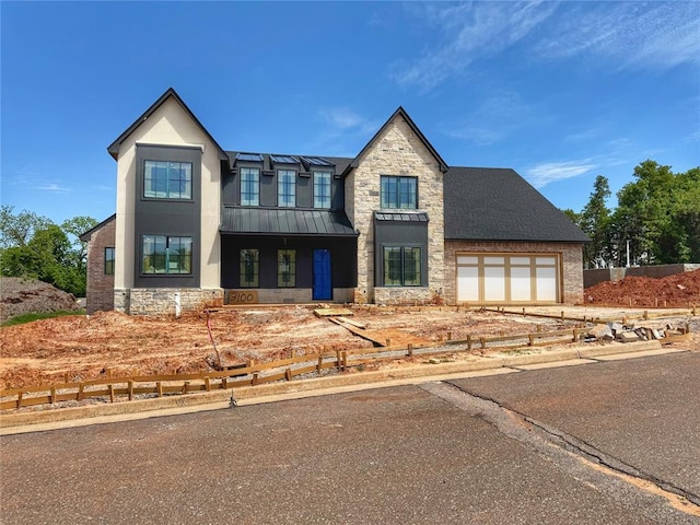 view of front of property with a standing seam roof, metal roof, driveway, and stone siding