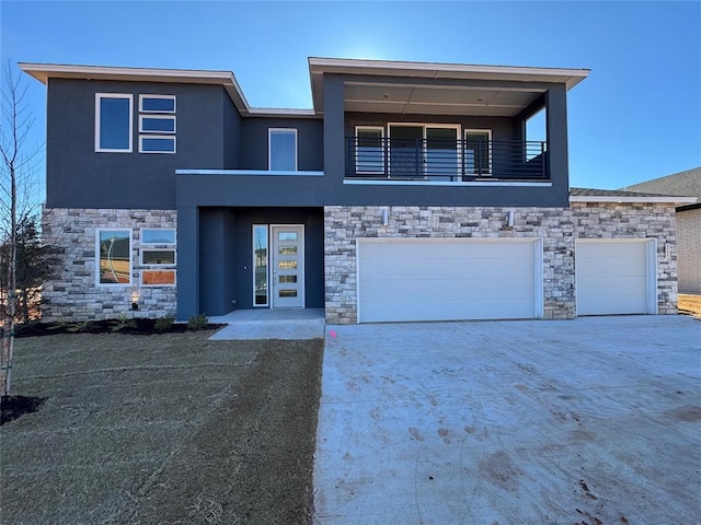 view of front of home featuring concrete driveway, a balcony, stone siding, and stucco siding
