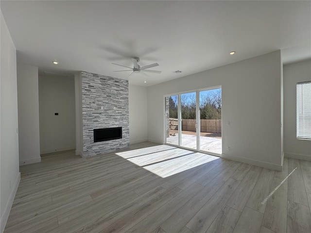 unfurnished living room featuring baseboards, a ceiling fan, light wood finished floors, and a fireplace
