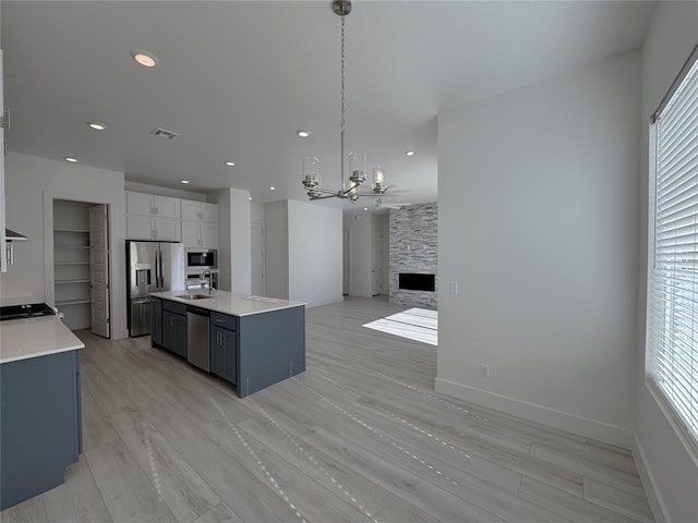 kitchen with light countertops, a chandelier, appliances with stainless steel finishes, and a kitchen island with sink