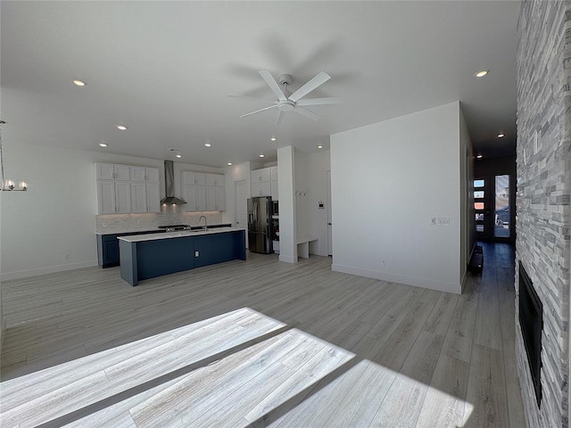 unfurnished living room with a sink, ceiling fan with notable chandelier, recessed lighting, and light wood-style flooring