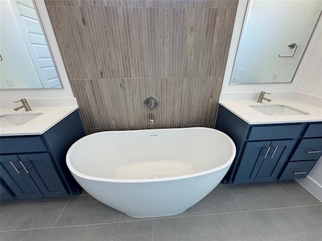 full bath with a freestanding tub, two vanities, a sink, and tile patterned flooring