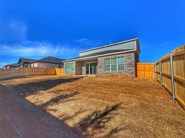 back of property featuring brick siding and a fenced backyard