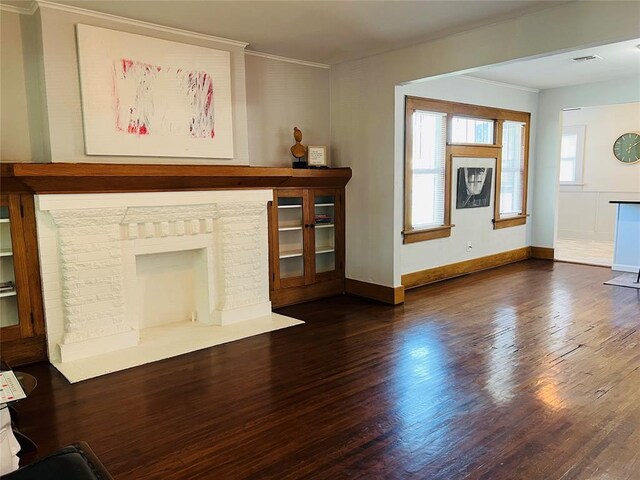 unfurnished living room with visible vents, ornamental molding, baseboards, and wood finished floors