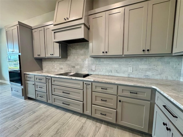 4129 Sambar St, Tuttle, OK 73089 - kitchen featuring gray cabinetry, black electric stovetop, light wood finished floors, and backsplash