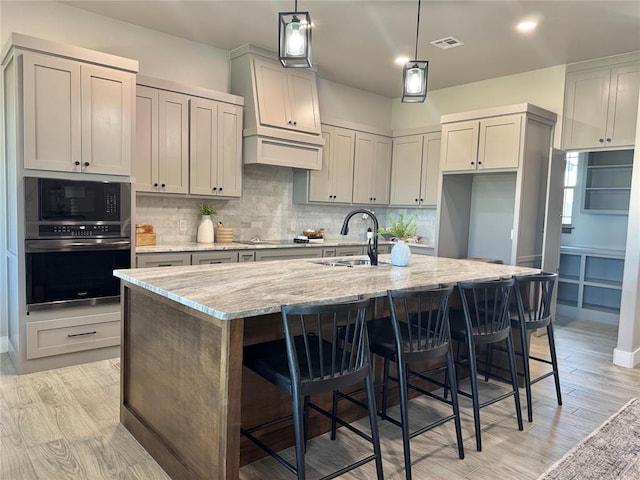 4129 Sambar St, Tuttle, OK 73089 - kitchen with black appliances, light stone countertops, backsplash, a center island with sink, and a breakfast bar area