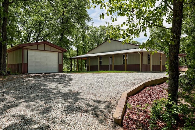 view of front of house featuring an outdoor structure, a detached garage, and driveway