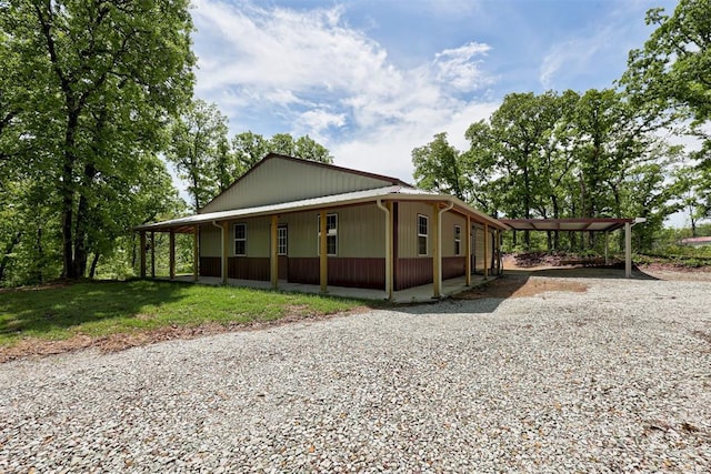 view of front of property with a porch, gravel driveway, and a detached carport