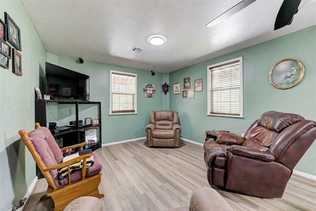 living area with visible vents, wood finished floors, and baseboards