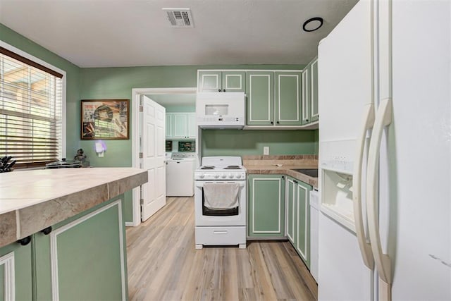 kitchen with visible vents, green cabinetry, white appliances, and washer / clothes dryer