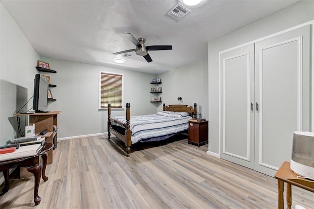 bedroom featuring light wood finished floors, a ceiling fan, visible vents, and baseboards