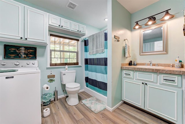 full bath featuring vanity, washer / dryer, toilet, visible vents, and wood finished floors