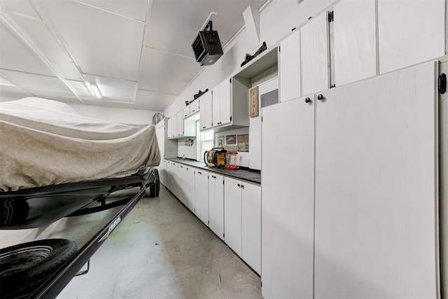 kitchen featuring dark countertops, finished concrete flooring, and white cabinetry