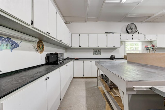 kitchen with white cabinetry, dark countertops, and finished concrete floors