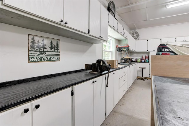 kitchen featuring concrete floors, dark countertops, and white cabinets