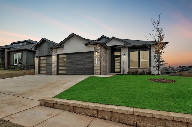 prairie-style house with a lawn, brick siding, fence, concrete driveway, and an attached garage
