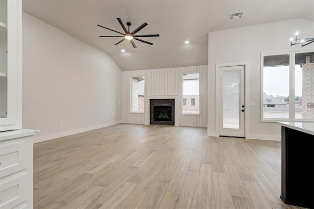 unfurnished living room with ceiling fan, a fireplace, light wood-style flooring, lofted ceiling, and visible vents