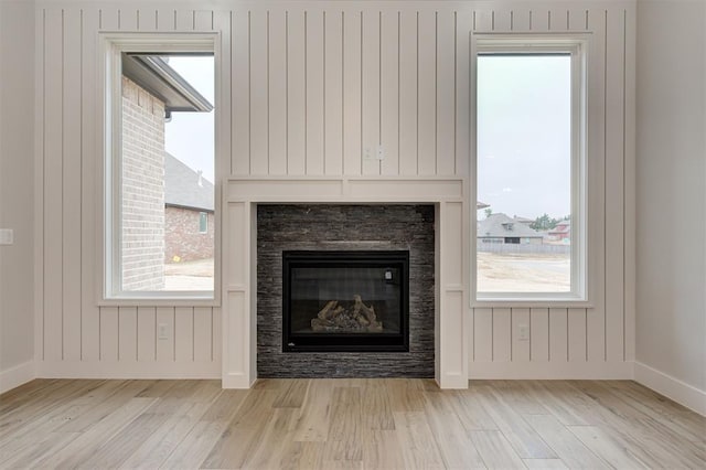 interior details with baseboards, a glass covered fireplace, and wood finished floors