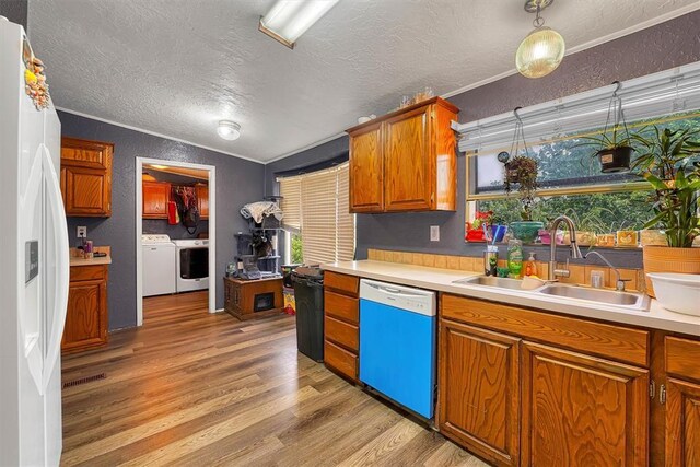 kitchen with a textured ceiling, light wood-type flooring, a sink, dishwashing machine, and a textured wall
