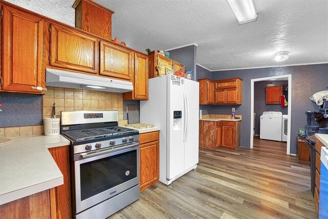 kitchen with white refrigerator with ice dispenser, stainless steel gas range oven, light countertops, under cabinet range hood, and light wood-style flooring