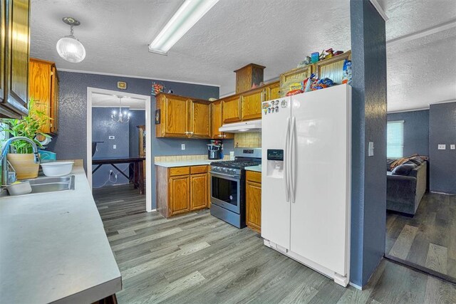 kitchen with a textured ceiling, a sink, gas stove, and white fridge with ice dispenser