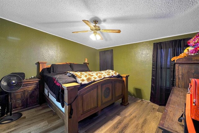 bedroom featuring a textured ceiling, a textured wall, a ceiling fan, and wood finished floors