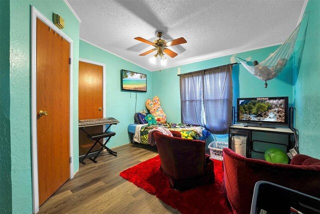 bedroom featuring a textured wall, a textured ceiling, a ceiling fan, wood finished floors, and ornamental molding