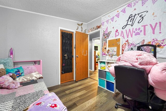 bedroom with crown molding, a textured ceiling, a textured wall, and wood finished floors