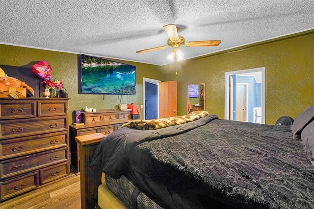 bedroom featuring a textured ceiling, a textured wall, ceiling fan, and light wood-style floors