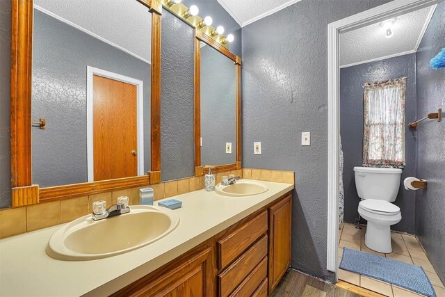 full bath featuring a sink, a textured wall, a textured ceiling, and crown molding