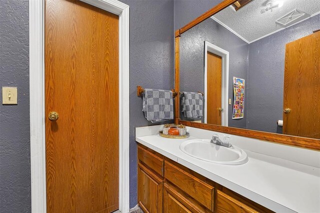 bathroom featuring vanity, a textured ceiling, and a textured wall