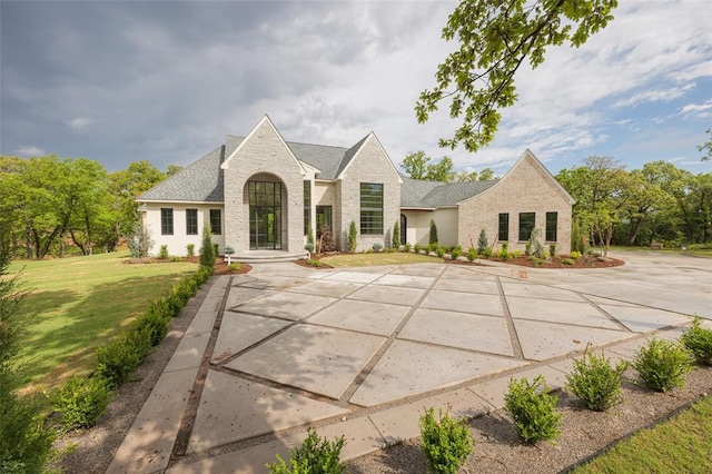french provincial home with a front lawn and stone siding
