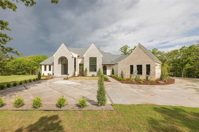 french country home featuring brick siding and a front lawn