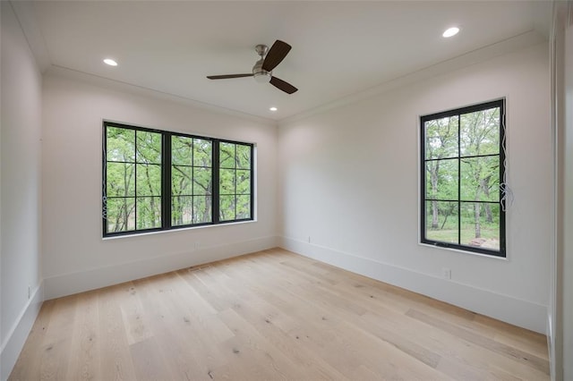 spare room featuring baseboards, ornamental molding, ceiling fan, and light wood-style flooring