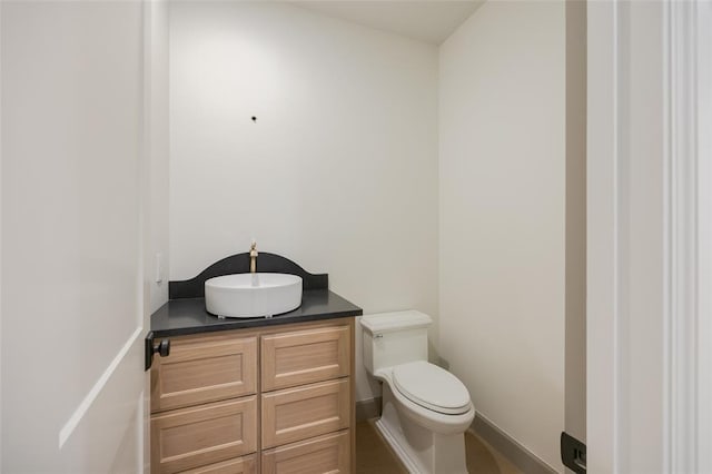 bathroom with toilet, vanity, and baseboards
