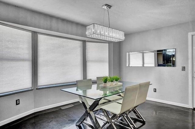dining space featuring baseboards, concrete floors, a chandelier, and visible vents