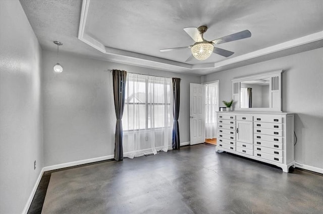 unfurnished room with a ceiling fan, baseboards, and a raised ceiling