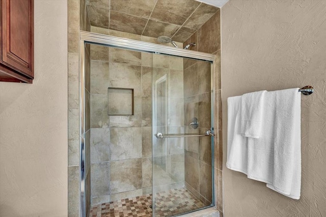 bathroom featuring a textured wall and a stall shower