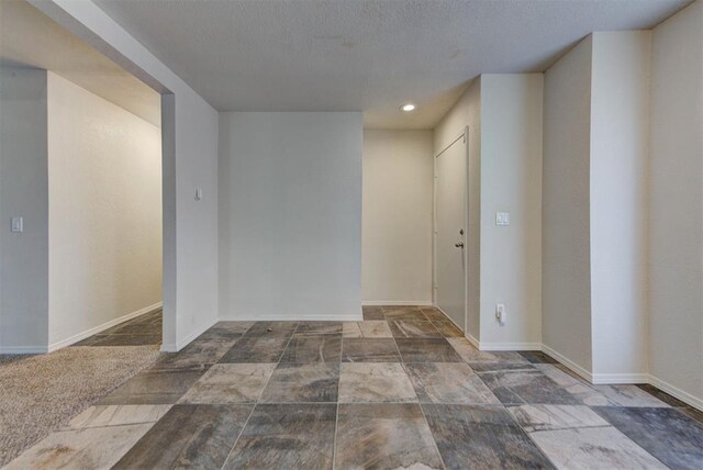 unfurnished room with baseboards, recessed lighting, a textured ceiling, and stone finish floor