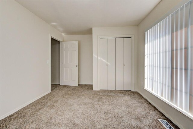 unfurnished bedroom with baseboards, carpet, a closet, and visible vents