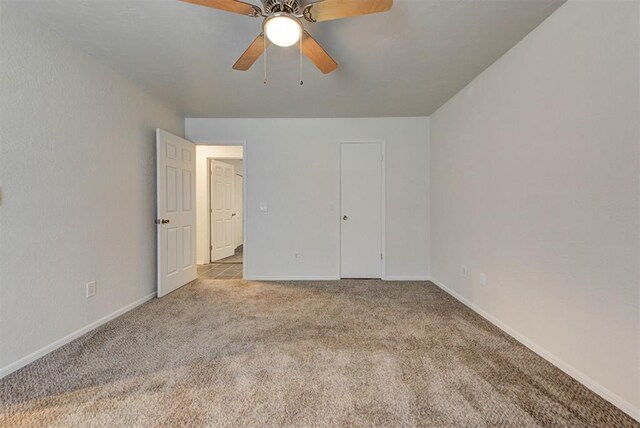 unfurnished bedroom with baseboards, a ceiling fan, and carpet