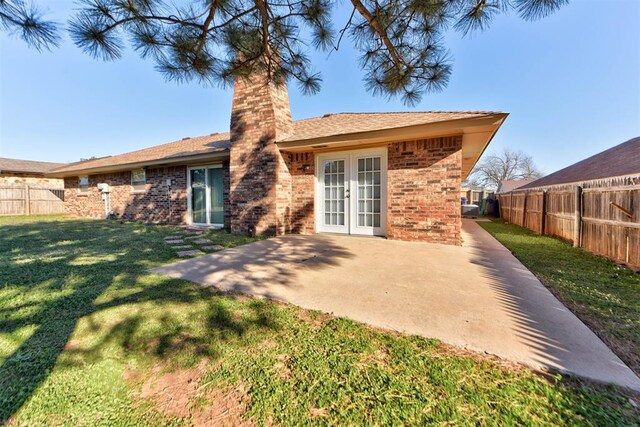 rear view of property with a patio, a fenced backyard, a lawn, and a chimney