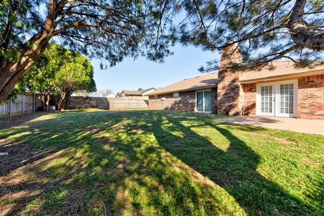 view of yard with a patio, a fenced backyard, and french doors