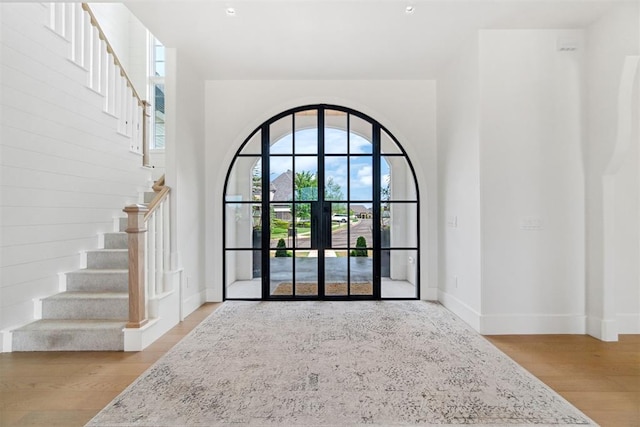 entryway with wood finished floors, baseboards, and stairs