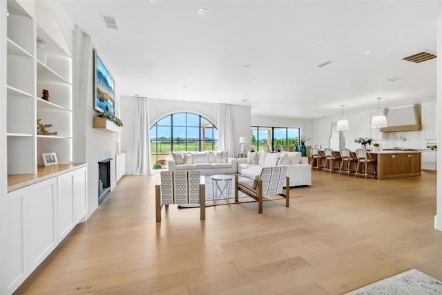 living room featuring a fireplace, visible vents, and light wood-style floors