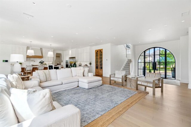 living area featuring visible vents, light wood-type flooring, and stairs