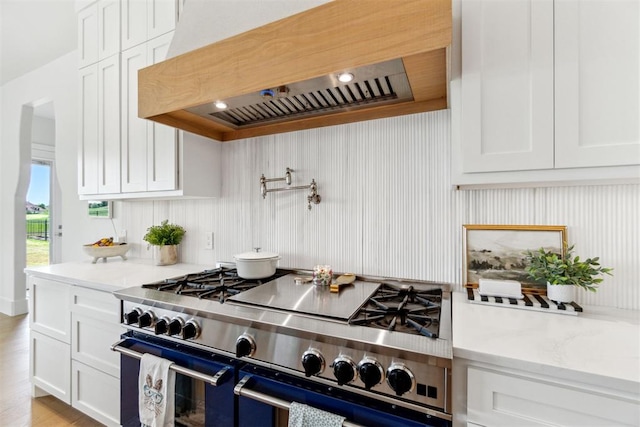 kitchen with premium range hood, light stone countertops, range with two ovens, and white cabinetry