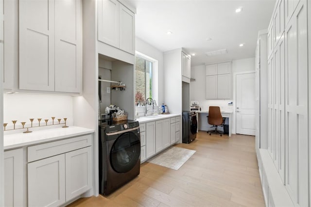 clothes washing area with washer / dryer, recessed lighting, light wood-style flooring, and a sink