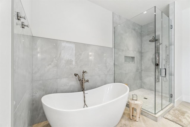 full bath featuring tile walls, a freestanding tub, and a shower stall