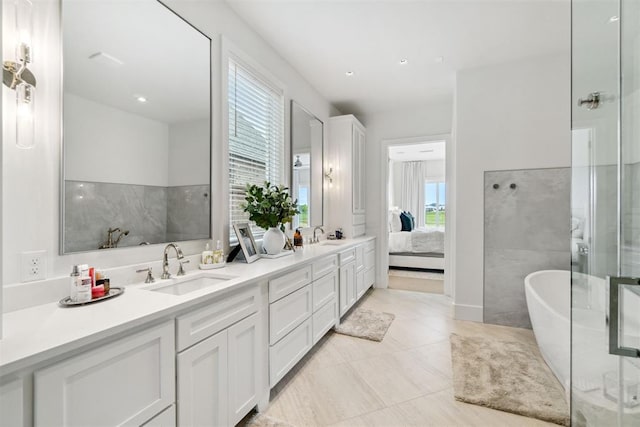 full bath featuring a sink, double vanity, ensuite bathroom, a freestanding bath, and tile patterned flooring